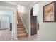 Hallway with staircase leading to the upper level and doorway into another room with stainless refrigerator at 16104 Bridgedale Dr, Lithia, FL 33547