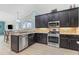 Open kitchen has stainless steel appliances, dark wood cabinets, and granite countertops at 16104 Bridgedale Dr, Lithia, FL 33547