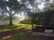 Spacious backyard featuring a screened-in porch, lush green grass, and a mature shade tree at 1841 Georgia Ave, Palm Harbor, FL 34683