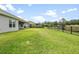 Large backyard with green grass and a black fence near a pond at 19819 Tattnall Way, Brooksville, FL 34601