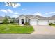 Charming single-story home with a well-manicured lawn and a brick driveway leading to a two-car garage at 19819 Tattnall Way, Brooksville, FL 34601