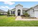 Inviting front entrance with arched detail and brick pathway framed by manicured landscaping and lush green lawn at 19819 Tattnall Way, Brooksville, FL 34601