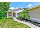 Inviting home entrance with a beautifully landscaped yard and concrete walkway to the front door at 22943 Sills Loop, Land O Lakes, FL 34639