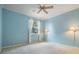 Bedroom featuring blue walls, carpeted floors, a ceiling fan, and window with light-colored curtains at 2354 Messenger Cir, Safety Harbor, FL 34695