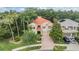 A two-story home with a tile roof, a manicured lawn, mature trees, and a brick driveway at 2354 Messenger Cir, Safety Harbor, FL 34695