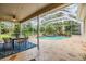 Outdoor covered patio featuring a dining set overlooking a screened pool with a rock waterfall and tropical landscaping at 2354 Messenger Cir, Safety Harbor, FL 34695