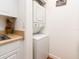 Clean laundry area with a stainless steel sink and a stacked washer and dryer setup at 2597 Countryside Blvd # 210, Clearwater, FL 33761