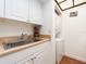 Bright laundry room with a stainless steel sink, white cabinets, and a stacked washer and dryer unit at 2597 Countryside Blvd # 210, Clearwater, FL 33761