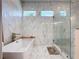 Modern bathroom with marble-style tile, a free-standing tub, and a glass-enclosed shower at 2890 Alexandria Marie Ln, Lutz, FL 33559