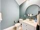 Charming powder room featuring a white vanity, round mirror, and stylish fixtures at 2890 Alexandria Marie Ln, Lutz, FL 33559