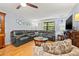 This cozy living room offers ample seating, a ceiling fan, and a view of the surrounding trees at 2919 Fig Ct, Palm Harbor, FL 34684