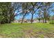 Large backyard featuring mature shade trees, green grass, and the rear exterior of the home at 2956 Sutherland Ct, Palm Harbor, FL 34684