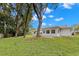 Large backyard featuring mature shade trees, green grass, and the rear exterior of the home at 2956 Sutherland Ct, Palm Harbor, FL 34684