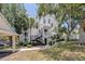 Exterior view of the two-story condo building with inviting stairs, landscaping, and covered parking at 3301 Haviland Ct # 203, Palm Harbor, FL 34684