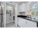 Contemporary kitchen area with stainless steel refrigerator, granite counters, and laundry closet with washer and dryer at 3301 Haviland Ct # 203, Palm Harbor, FL 34684