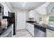 Galley-style kitchen featuring stainless steel appliances, granite countertops, white cabinetry, and open view into the living area at 3301 Haviland Ct # 203, Palm Harbor, FL 34684