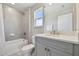 Modern bathroom with gray tile and a bright window above the toilet and bath/shower at 33287 Sycamore Leaf Dr, Wesley Chapel, FL 33545