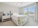 Bedroom featuring a large bed, a ceiling fan, and sun-filled windows with a view of the neighborhood at 33287 Sycamore Leaf Dr, Wesley Chapel, FL 33545
