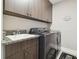 Laundry room features wood cabinets, granite countertops, utility sink, and modern washer and dryer at 33287 Sycamore Leaf Dr, Wesley Chapel, FL 33545