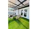 Covered patio features artificial turf and a dining table with chairs near french doors at 4049 Ponea Dr, Sarasota, FL 34241