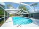 Screened-in pool with clear water, surrounded by a white patio, and lush greenery beyond at 415 Mission Hills Ave, Temple Terrace, FL 33617