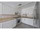 Well-lit kitchen featuring stainless steel appliances, granite countertops, tiled backsplash, and white cabinets at 4463 Vieux Carre Cir, Tampa, FL 33613