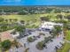 An aerial view of a building surrounded by a parking lot and a lush green golf course located at Ardea Country Club at 465 Holly Hill Rd, Oldsmar, FL 34677