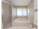 Bright bathroom featuring a soaking tub with white tile surround and a glass-enclosed shower at 465 Holly Hill Rd, Oldsmar, FL 34677