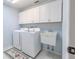 Bright laundry room featuring white appliances, utility sink, and upper cabinets at 465 Holly Hill Rd, Oldsmar, FL 34677