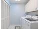 Bright laundry area with tile flooring, storage cabinets, and modern, front-loading washer and dryer at 465 Holly Hill Rd, Oldsmar, FL 34677