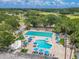 Aerial shot showcasing community pool with lap lanes, pool, sun loungers with umbrellas, and surrounding trees at 465 Holly Hill Rd, Oldsmar, FL 34677