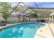 Refreshing screened-in pool with blue tile accents, surrounded by lounge furniture and a barbecue grill at 465 Holly Hill Rd, Oldsmar, FL 34677