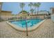 Inviting community pool surrounded by a white fence, tropical palm trees and building exteriors at 4708 Michael Ct # 104, Tampa, FL 33614