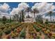 A beautifully landscaped entrance to Esplanade at Wiregrass Ranch features colorful flowers and palm trees at 4795 Freccia Loop, Wesley Chapel, FL 33543