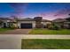 Beautiful single-Gathering home boasting stone accents, a tile roof, and well-maintained lawn at dusk at 4795 Freccia Loop, Wesley Chapel, FL 33543