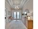 Bright foyer with chandelier, tray ceiling, white double doors, console table, and decorative mirror at 4795 Freccia Loop, Wesley Chapel, FL 33543