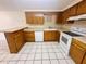 Functional kitchen featuring wood cabinetry, white appliances, and tile flooring at 4836 Daphne St, New Port Richey, FL 34652