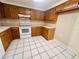 Well-lit kitchen featuring plenty of wooden cabinets and white appliances set against tile flooring at 4836 Daphne St, New Port Richey, FL 34652