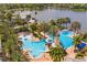 High angle shot of community pool near lake with palm trees, dock, and water slide and lighthouse features at 5102 Coastal Scene Dr, Apollo Beach, FL 33572