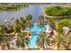 Aerial shot showcasing the pool, slide, lighthouse, lake, and dock, surrounded by lush landscaping and palm trees at 5102 Coastal Scene Dr, Apollo Beach, FL 33572