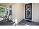 Cozy front porch featuring stylish tile flooring, two chairs and a view of the inviting front entrance at 5102 Coastal Scene Dr, Apollo Beach, FL 33572