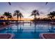 Beautiful swimming pool at sunset with palm trees and lounge chairs, offering a relaxing outdoor experience at 5102 Coastal Scene Dr, Apollo Beach, FL 33572