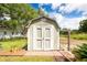 View of the painted, barn-style outbuilding with double doors and adjacent garden bed on a sunny day at 5675 Lown N St, St Petersburg, FL 33714