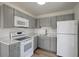 The modern kitchen is equipped with white appliances and shaker-style grey cabinetry at 6014 S 82Nd St, Tampa, FL 33619