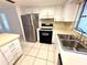 Well-lit kitchen with stainless steel refrigerator and ample countertop space for meal prep at 613 Sandy Hollow Rd, Tarpon Springs, FL 34689