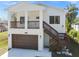 Exterior view of a white two-story home with a front porch, brown trim, and a ground-level garage at 6433 Werner Ave, New Port Richey, FL 34652