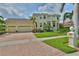 View of the two-story home featuring lush landscaping and a three-car garage at 6468 Rubia Cir, Apollo Beach, FL 33572