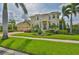 Two-story home showcasing lush landscaping, a paver driveway, a three-car garage, and a second-story balcony at 6468 Rubia Cir, Apollo Beach, FL 33572