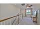 Well-lit upstairs hallway featuring carpet, wood railing and window with floral print curtains at 6468 Rubia Cir, Apollo Beach, FL 33572