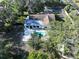 Aerial view of a home with a light-colored patio and swimming pool surrounded by mature trees at 6602 Winding Brook Dr, New Port Richey, FL 34655